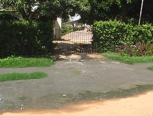 With raw sewerage blocking entry to their home through their front gate, occupants climb over a neighbour's fence for access to their home.